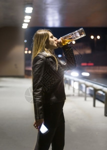 年轻女子的肖像从酒瓶和夜里喝威士忌背景图片