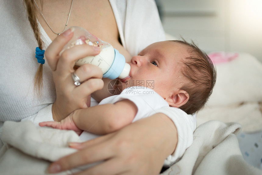 母亲用瓶子喂养新生儿的近身肖像图片