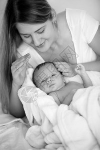 年轻母亲与婴儿男孩在床上摆布的黑白年轻母亲肖像图片