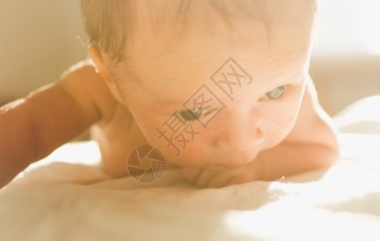 阳光明媚的天在床上爬的可爱新生婴儿触摸画像图片
