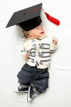穿着毕业帽子躺在床上的可爱小男孩肖像图片