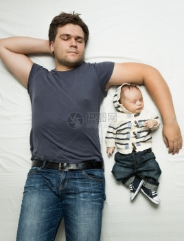 睡在床上的时尚父亲和婴儿男孩的顶端肖像图片