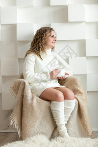 穿着白色毛衣的美女坐在椅子上喝茶图片