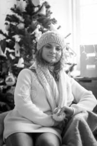 坐在圣诞树附近椅子上的可爱卷女人的黑白画像图片