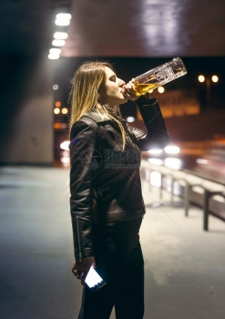 孤独的女子在高速公路上喝酒瓶的肖像图片