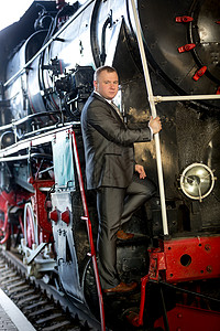 高贵的男人坐在旧蒸汽列车的楼梯上图片