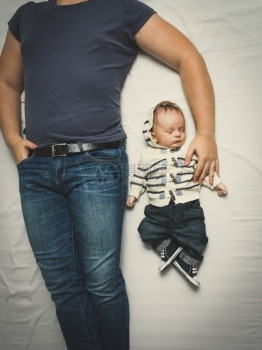 身穿牛仔裤睡在床上的父亲和小儿子顶端镜头图片