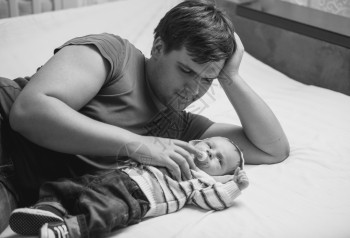 年轻父亲与新生儿躺在床上的黑白画像图片