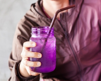 女手持冰饮用紫玻璃配有旧过滤器股票照片图片