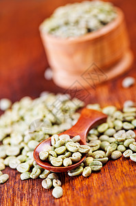 碗里和桌子上绿咖啡豆高清图片