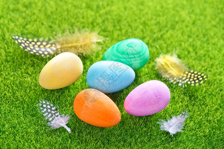 绿草坪上的彩色鸡蛋和羽毛背景图片