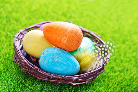 鸟窝和彩色鸡蛋在绿草坪上图片
