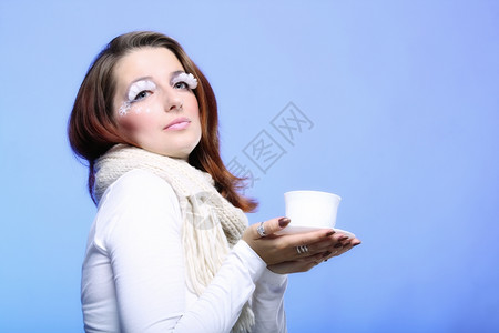 时装女尚的冬天化妆品拿着一杯热饮酒享受咖啡时间复制蓝色背景图片