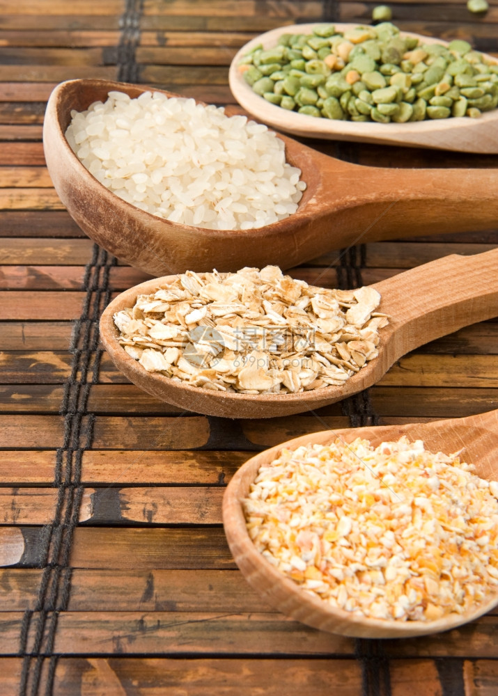 稻草桌上的木勺中燕麦大米和豆子图片