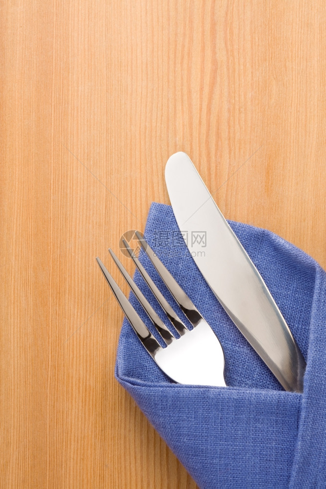 银叉和刀作为木制背景的餐巾中用具图片