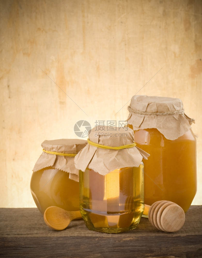 罐装蜂蜜和粘在木本上图片