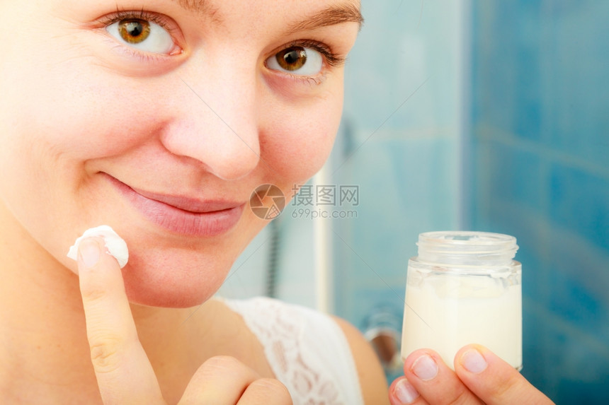 女使用湿润的皮肤奶油护理年轻女在脸上使用净湿润的皮肤奶油女孩使用干皮层润湿剂图片