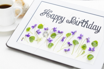 生日快乐贺卡用Viola花和叶子在数字平板电脑上加咖啡杯的笔迹图片