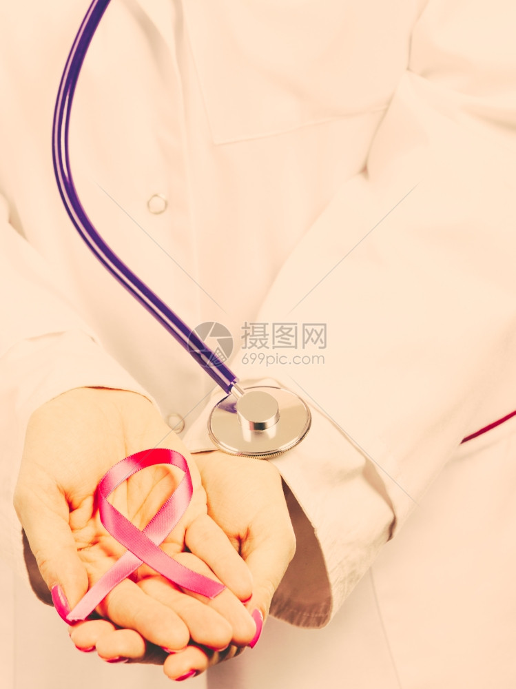 带粉色丝的女医生听诊器的女医生手里握着粉色癌症的乳房丝带有患病意识被过滤图片