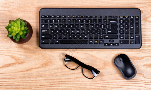 由计算机键盘婴儿老鼠和阅读眼镜组成的清洁办公桌顶部视图图片