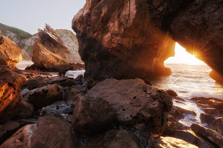 太阳光穿过葡萄牙Ursa海滩的岩石拱门图片