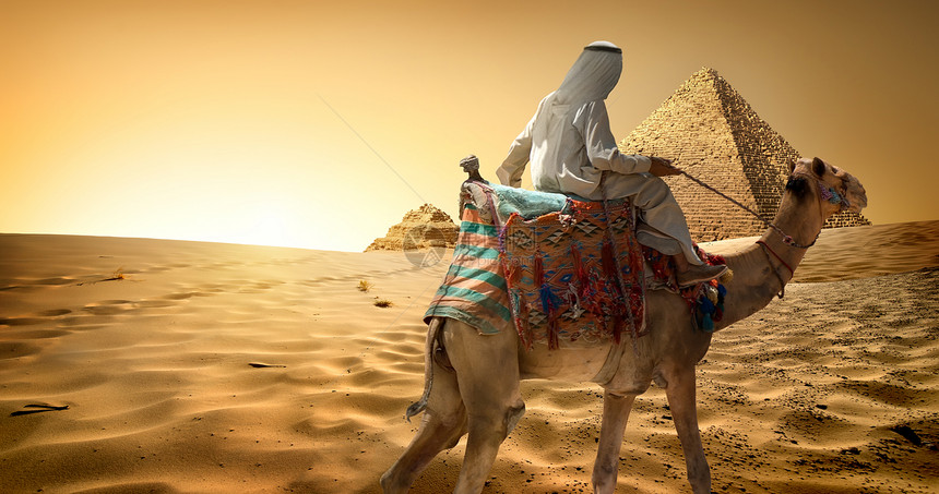 在金字塔附近沙漠中骑骆驼的贝都因人图片
