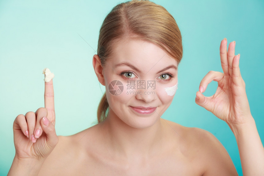 美容治疗女当面使用润湿奶油护肤产品制作绿色蓝背景的图片