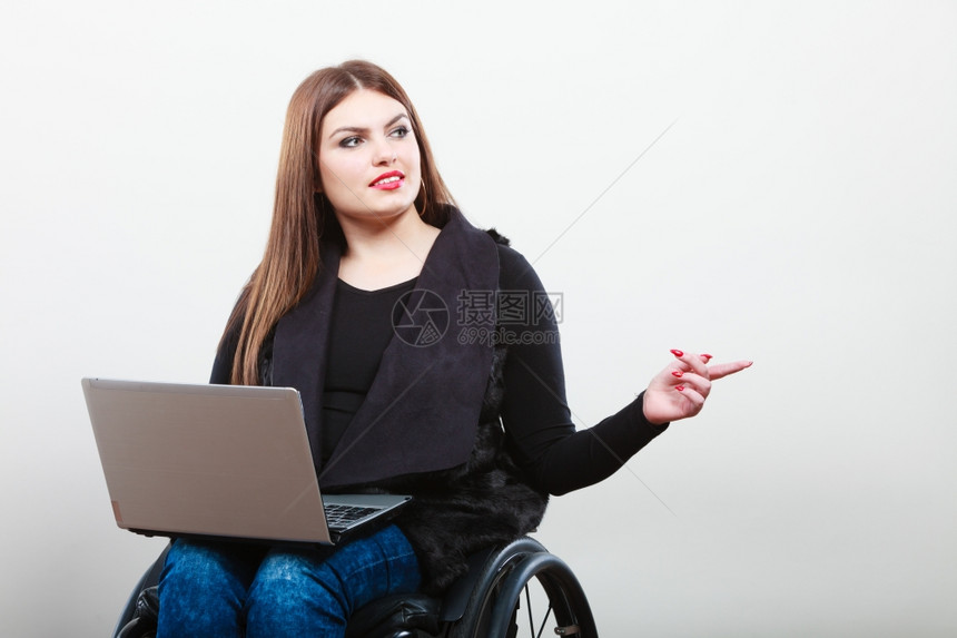 手持膝上型计算机的残疾妇女技术和移动设备手持膝上型计算机的残疾女孩手持轮椅的年轻女商人图片