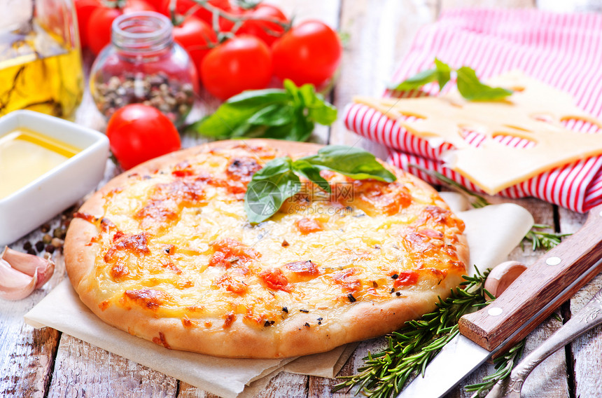 桌子上加番茄和奶酪的比萨饼图片