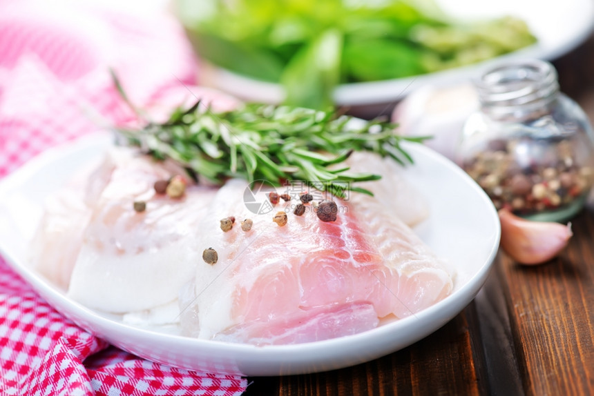 餐桌上带香料和胡椒的生鱼图片