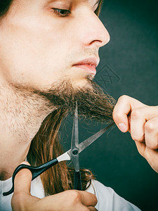 长胡子拿着剪刀的年轻人男孩在下巴上剪头发图片
