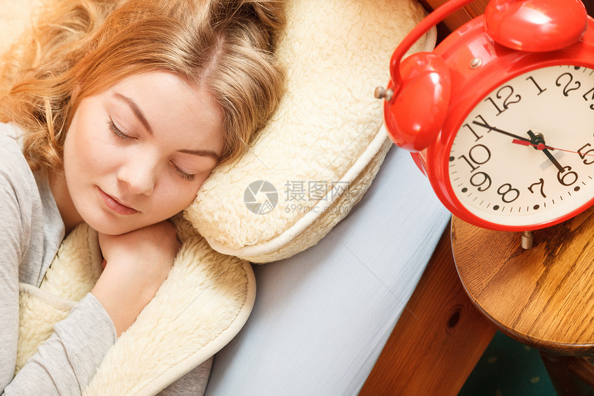 睡在床上的妇女与固定闹钟睡在羊毛毯下的妇女与固定闹钟图片
