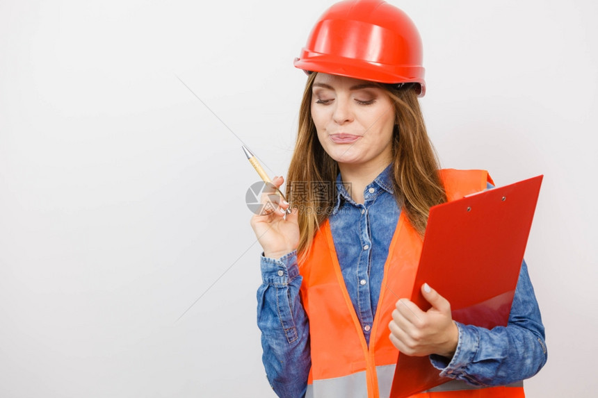 女建筑工人结构程师穿橙色背心红硬头盔的建筑工结构程师持有笔文件垫工业作安全室中图片