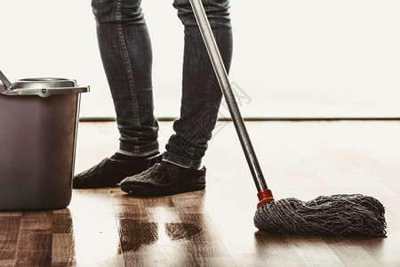 关闭人清洗地板在家用拖把和桶的人清理房子图片