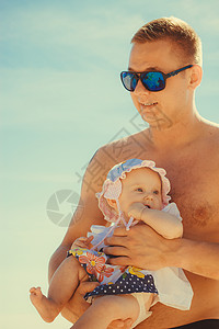 男人抱着女婴在海滩度假图片
