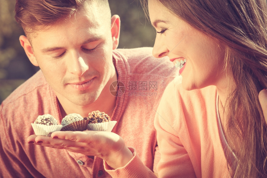 情侣约会爱和迷人的女给帅哥送蛋糕饼干在户外约会快乐的情侣图片