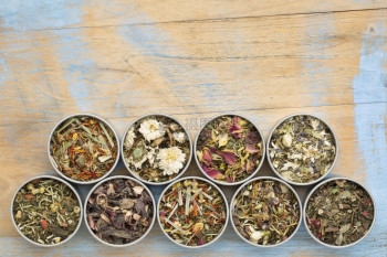 在圆金属罐中收集9个草药混合的茶叶与带复制空间的涂漆粗木顶视图图片