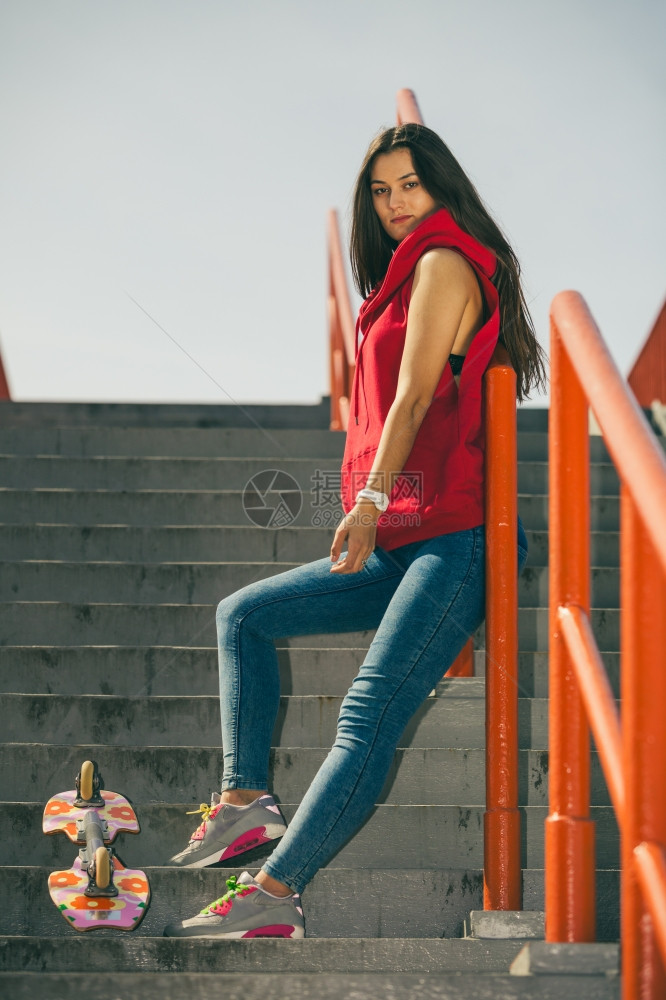 城市滑板女孩穿着的酷长发女孩穿着滑板的酷女孩靠在城市楼梯上扶手图片