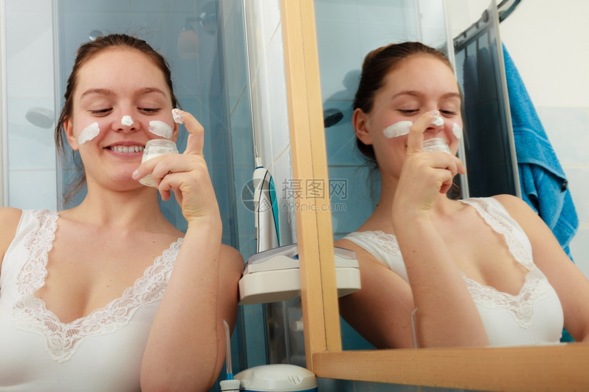 女使用湿润的皮肤奶油护理快乐的年轻女在脸上使用净湿润的皮肤奶油女孩使用干皮层润湿剂图片