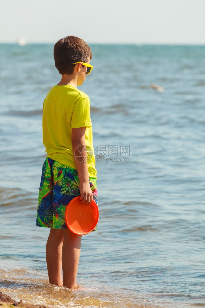 小男孩玩飞盘在海滩上玩得开心图片