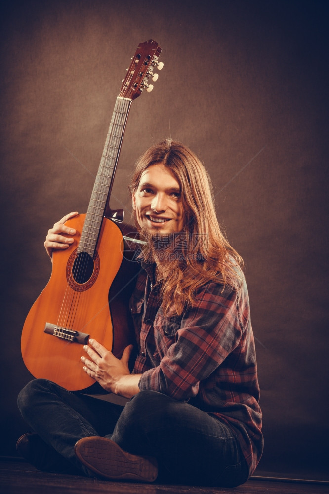 音乐爱好概念笑吉他手的乐器年轻人穿着漂亮的衬衫和吉他坐在地板上图片