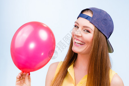 带着红气球快乐的少女带着红色粉气球笑的少女穿着时装的年轻迷人女穿着蓝色背景的时装背景图片