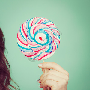 女手拿着多彩的棒糖甜食和享受的概念工作室拍摄了绿色蓝背景图片