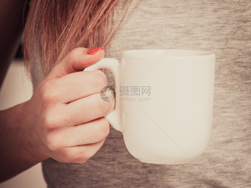 妇女红指甲的女手握着咖啡享受舒适图片