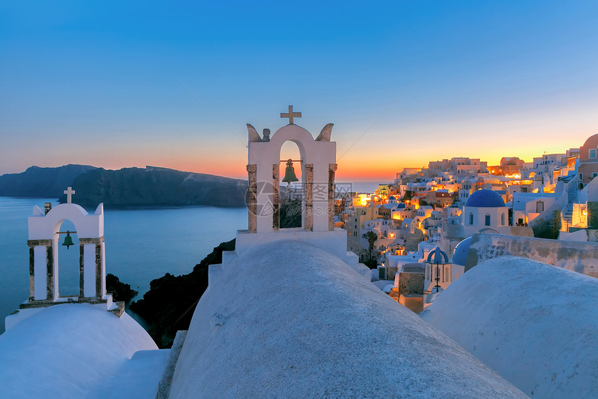 希腊圣托里尼岛Oia或Ia日落时的Oia或Ia有钟白房子和教堂的拱门白房子和教堂有蓝色圆丘图片