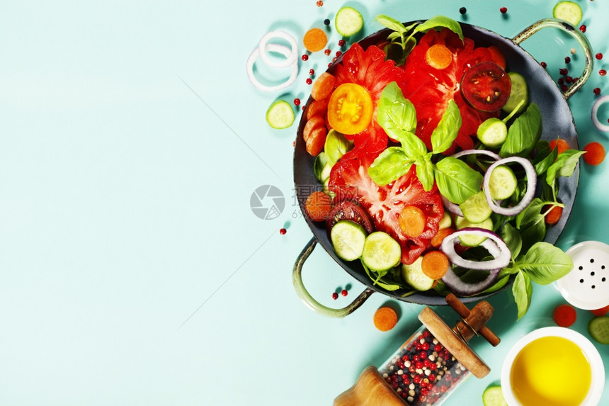 蓝色背景的新鲜沙拉番茄洋葱胡萝卜巴西尔黄瓜盐和胡椒图片
