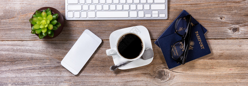 计划乘坐深咖啡护照眼镜手机计算键盘和安装在生动桌面上的深咖啡计算机键盘和装置背景图片