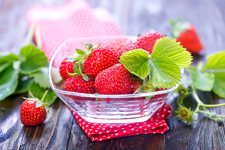 新鲜草莓在碗里和桌子上图片