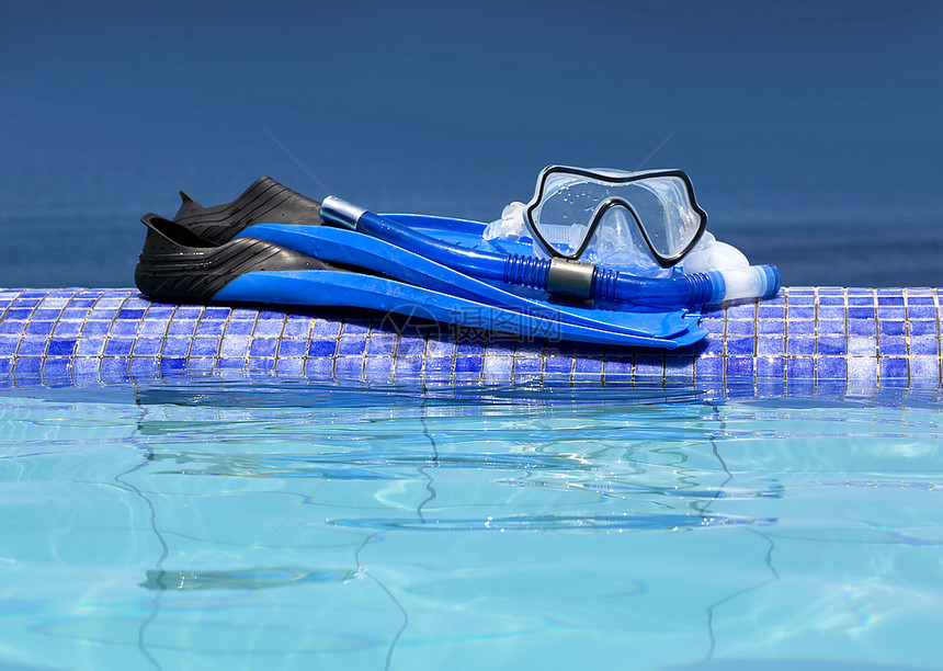 在游泳池背景上戴蓝脚套的Scuba面具图片