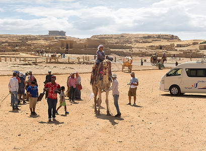 2015年8月3日埃及吉萨骆驼附近的旅游者和埃及沙漠金字塔的废墟图片